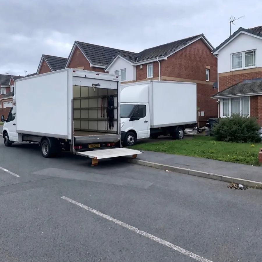 Two Surrey Prestige Removals box vans parked outside a house during a move