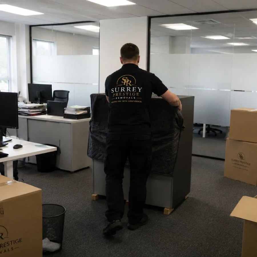 Surrey Prestige Removals team member moving office furniture wrapped for protection